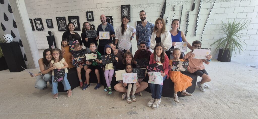Families and Vanessa Teodoro holding collaborative artworks inside the MOTHER exhibition in Lisbon.